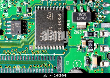 Nahaufnahme einer Computerplatine, die verschiedene Größen integrierter Chips und anderer elektronischer Komponenten zeigt. Stockfoto