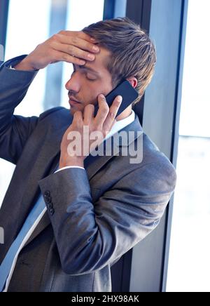 Das bringt mich in eine unangenehme Position. Aufnahme eines hübschen jungen Geschäftsmannes, der bei der Arbeit mit seinem Mobiltelefon spricht. Stockfoto