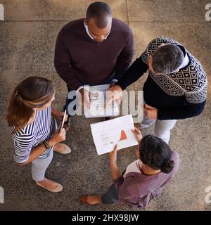 Strategische Entscheidungen im Team treffen. Aufnahme einer Gruppe von Kollegen, die in einem Meeting über Papierkram diskutieren. Stockfoto