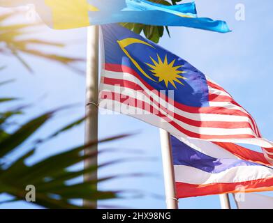 Hoch fliegen, stolz fliegen. Aufnahme einer malaysischen und thailändischen Flagge, die im Wind weht. Stockfoto