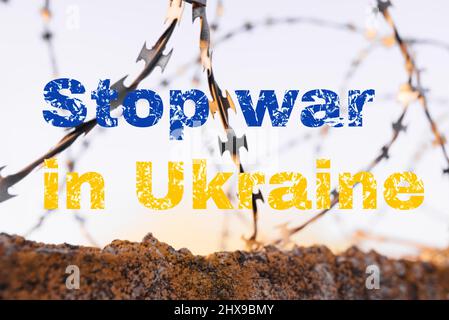 Beendet den Krieg in der Ukraine. Inschrift auf einem Hintergrund aus Stacheldraht und blauem Himmel. Russlands Invasion der Ukraine, eine Bitte um Hilfe in der ganzen Welt Stockfoto
