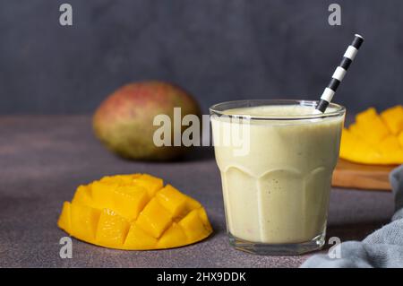 Lassi Mango in Glas auf braunem Hintergrund. Indisches gesundes ayurvedisches kaltes Getränk mit Mango, Close-Up Stockfoto