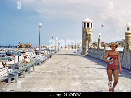 Frau in Badeanzug zu Fuß auf Zement Promenade in unberechtigtem Florida Stadt Ca. 1950s Stockfoto