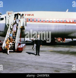 Passagiere, die ein TWA-Flugzeug auf einer asphaltierten Flughafenbahn verlassen, ca. 1971 Stockfoto