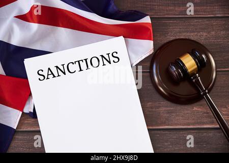 Britische Sanktionsliste gegen Russland, Richtergavel, Flagge des Vereinigten Königreichs auf Holztisch. Stockfoto
