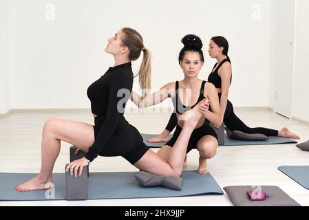 Konzentrierter professioneller weiblicher Yogalehrer hilft einer jungen Schülerin, die richtige Position einzunehmen, gibt motivierten s eine Meisterklasse Stockfoto