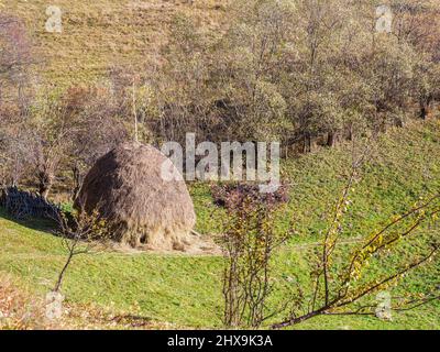 Rustikale ländliche Landschaft in einem romantischen Dorf mit einem Heuhaufen auf dem Feld. Stockfoto