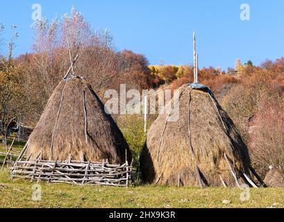Rustikale ländliche Landschaft in einem romantischen Dorf mit einem Heuhaufen auf dem Feld. Stockfoto