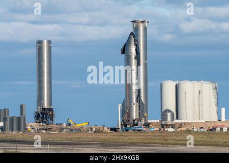 Ein Raumschiff und zwei zylindrische Super Heavy Booster-Raketen auf der Startrampe SpaceX in Boca Chica, Texas. Das Raumschiff ist 160' groß, während das S Stockfoto