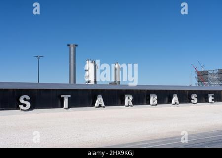 Das Schild an der SpaceX Starbase in Boca Chica in der Nähe von Brownsville, Texas. Dahinter steht ein Raumschiff und eine Super Heavy Booster Rakete. Stockfoto