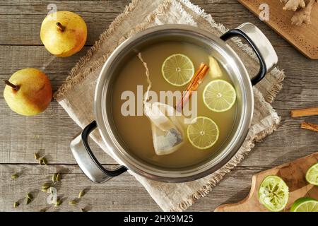 Ein Topf gefüllt mit Birnensaft, Limette und Gewürzen - Vorbereitung eines hausgemachten heißen Getränks Stockfoto