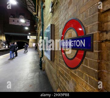 Bahnsteig der Londoner U-Bahn-Linie Paddington, auf dem das Londoner U-Bahn-Rundlogo mit wartenden Passagieren abgebildet ist Stockfoto