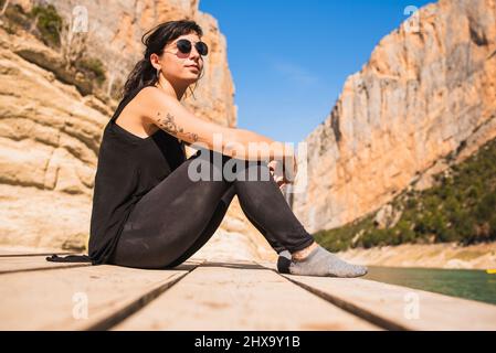 Junge Frau, die während einer Kajaktour auf einem Steg sitzt. Stockfoto