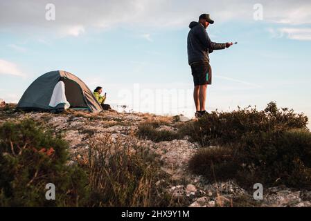 Das Paar zeltete am Rande einer Klippe und genoss den Sonnenuntergang. Stockfoto