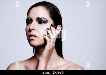 Scharfe und atemberaubende Schönheit. Aufnahme einer schönen jungen Frau, die ein metallisches Make-up und einen Nagellack trägt. Stockfoto