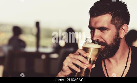 Bärtiger Mann trinkt Lagerbier. Älterer Mann trinkt Bier mit Überraschungsgesicht. Der Mann hält ein Glas Bier. Stockfoto