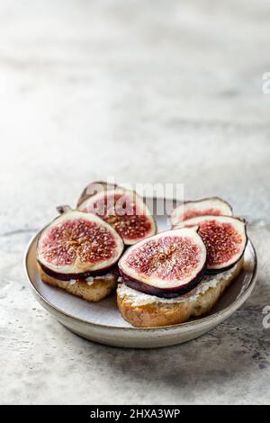 Zwei Sandwiches mit Feigen, Käse, Thymian und Honig auf dem Teller auf strukturiertem Hintergrund. Speicherplatz kopieren. Vertikale Ausrichtung Stockfoto