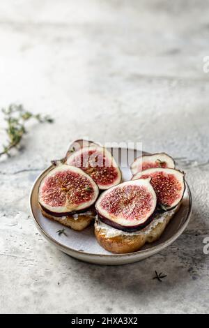 Zwei Sandwiches mit Feigen, Käse, Thymian und Honig auf dem Teller auf strukturiertem Hintergrund. Speicherplatz kopieren. Vertikale Ausrichtung Stockfoto