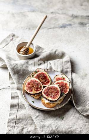 Zwei figurige Sandwiches mit Käse, Thymian und Honig auf Leinenserviette auf strukturiertem Hintergrund. Vertikale Ausrichtung. Speicherplatz kopieren Stockfoto