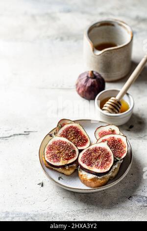 Zwei Sandwiches mit Feigen, Käse, Thymian und Honig auf dem Teller auf strukturiertem Hintergrund Stockfoto