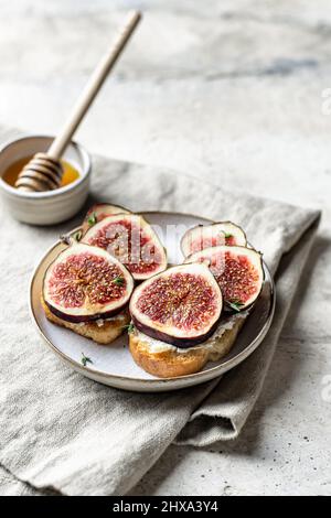 Zwei Sandwiches mit Feigen, Käse, Thymian und Honig auf Leinenserviette auf strukturiertem Hintergrund. Vertikale Ausrichtung. Speicherplatz kopieren Stockfoto