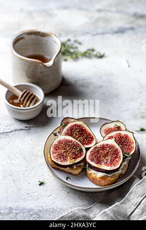 Zwei Sandwiches mit Feigen, Käse, Thymian und Honig mit Leinenserviette auf strukturiertem Hintergrund Stockfoto