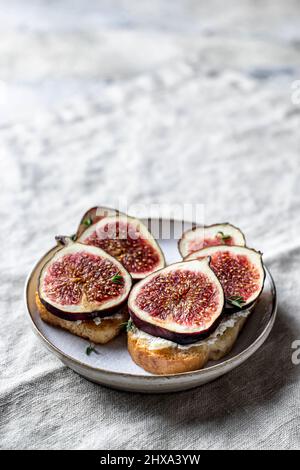 Zwei Sandwiches mit Feigen, Käse, Thymian und Honig auf einer grauen Leinenserviette. Nahaufnahme Stockfoto