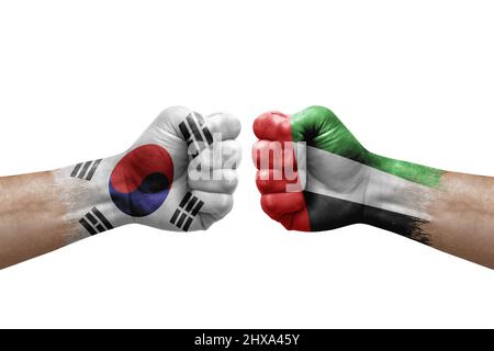 Zwei Hände schlagen sich gegenseitig auf weißem Hintergrund zu. Länderflaggen bemalten Fäuste, Konfliktkrisenkonzept zwischen Südkorea und den vereinigten arabischen emiraten Stockfoto