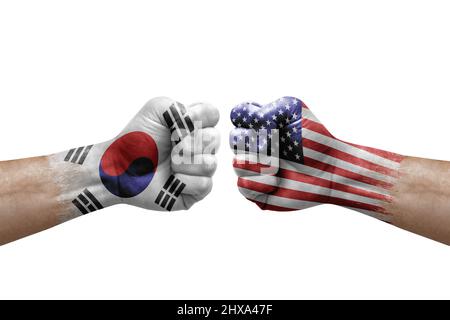 Zwei Hände schlagen sich gegenseitig auf weißem Hintergrund zu. Länderflaggen bemalten Fäuste, Konfliktkrisenkonzept zwischen Südkorea und den usa Stockfoto