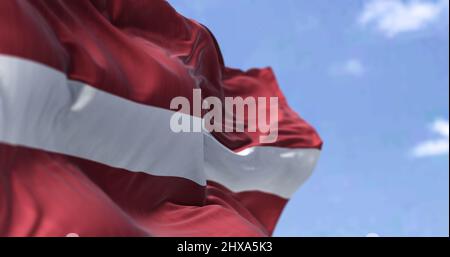 Detail der Nationalflagge Lettlands, die an einem klaren Tag im Wind winkt. Lettland ist ein Land im Ostseeraum Nordeuropas. Selektiver Fokus. Stockfoto