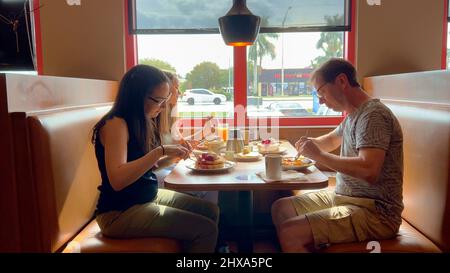 Eine Gruppe von Menschen, die in einem Restaurant - MIAMI, USA - Frühstück essen, 20. FEBRUAR 2022 Stockfoto