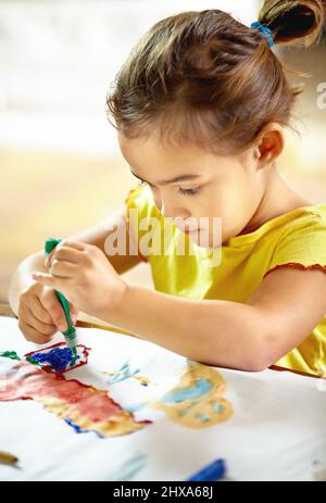 Kreativ werden mit Farben. Aufnahme eines entzückenden kleinen Mädchens, das beim Malen ein Chaos macht. Stockfoto