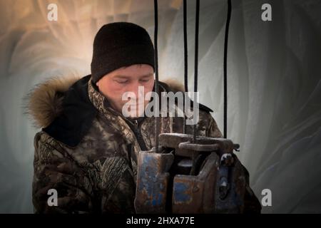 Der Schleuder zieht eine Bandschlinge am Haken eines LKW-Krans an Stockfoto