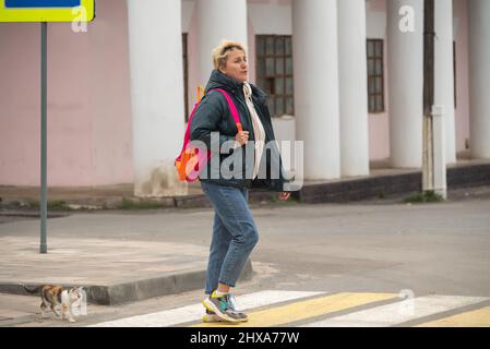 Ein Mädchen in legerer Kleidung überquert die Straße durch einen Fußgängerübergang. Stockfoto