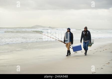 Wir machen uns auf den Weg zum Angeln. Aufnahme von zwei Freunden, die an einem frühen bewölkten Morgen fischen. Stockfoto