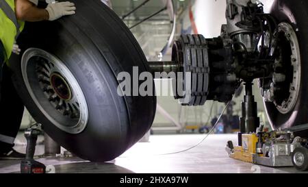 Flughafenmitarbeiter prüft Fahrgestell. Motor und Chassis des Passagierflugzeugs unter starker Wartung. Der Techniker überprüft das Chassis und den Motor des Flugzeugs Stockfoto