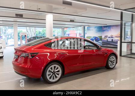 Innenraum des Tesla-Autosalons mit 2022 Tesla Modell 3 in Rot auf dem Display, Sydney, Australien Stockfoto