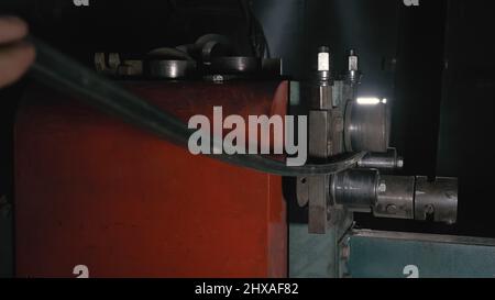 Schmiedewerkstatt auf dem Tisch. Schmiede manuelle Produktion. Arbeitnehmer Biegungen die Metallstange auf das schmiedeeiserne runde Biegemaschine. Herstellung von einem Designer p Stockfoto