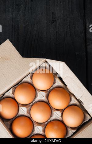 Braune Eier im Karton-Tablett-Set, auf schwarzem Holztisch-Hintergrund, Draufsicht flach liegend, mit Platz für Text-Copyspace Stockfoto