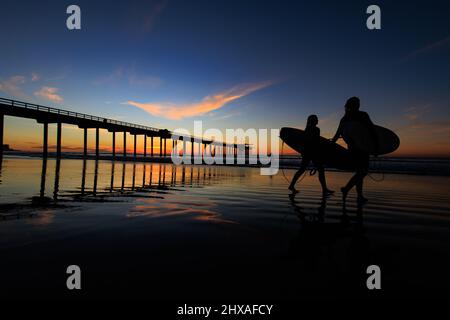 La JOLLA, KALIFORNIEN. 9. Februar 2021. Zwei junge Surferinnen beim Sonnenuntergang am Scripps Pier. Foto: Mark Johnson/Ironstring Stockfoto