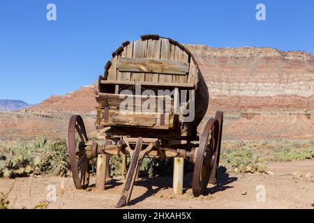 Isolierte Old Vintage Wooden Wild West Pioneer Stage Coach Wagon Wheel Replik mit Western Red Rock Canyon Cliffs Utah Landschaft im Hintergrund Stockfoto