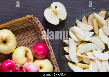 Äpfel und Glasschale zum Backen mit Äpfeln schneiden auf dem Holzhintergrund Stockfoto
