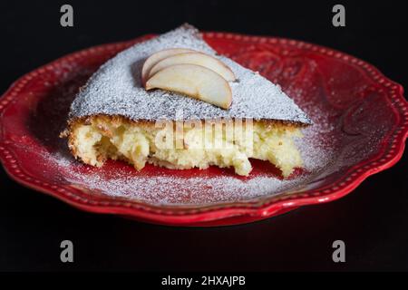Nahaufnahme Stück Apfelkuchen auf der roten Platte auf schwarzem Hintergrund Stockfoto