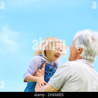 Großvater weiß immer, wie sie zum Lachen bringen soll. Aufnahme eines glücklichen Großvaters, der seine junge Enkelin hob. Stockfoto