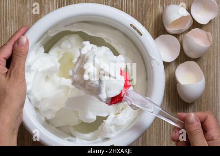Hand einer Frau, die geschlagenes Eiweiß zeigt Stockfoto