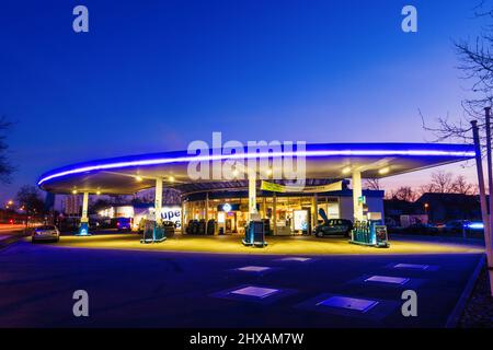 Freiburg Im Breisgau, Deutschland. 11. März 2022. Eine fast leere Tankstelle ist blau beleuchtet, während die Sonne im Hintergrund aufgeht. Ein Display zeigt die Preise für verschiedene Kraftstoffarten an. Die Kraftstoffpreise sind aufgrund des Krieges in der Ukraine auf einem Rekordhoch. Quelle: Philipp von Ditfurth/dpa/Alamy Live News Stockfoto