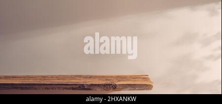 Holzregal auf einem Hintergrund beigefarbener Wand im Sonnenlicht Stockfoto