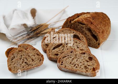 Traditionelles Dinkel-Sauerteig-Brot, in Scheiben geschnitten auf weißem Holzhintergrund, in Scheiben geschnitten Stockfoto