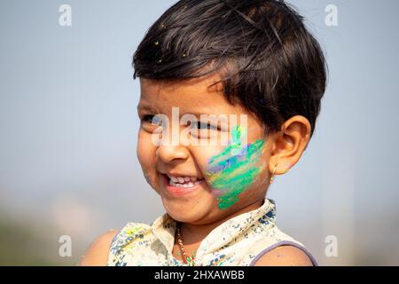 Glücklich lächelnd fröhliche kleine Mädchen Kind holi Farben auf Gesicht während holi Festival Feier. Stockfoto