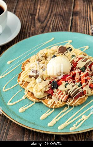 Herzwaffel mit Banane und Erdbeere mit Gummy Candy und Eis darauf Stockfoto